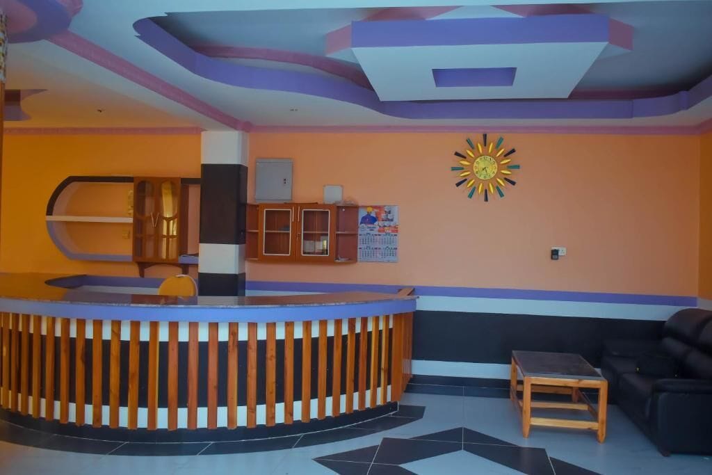 A reception area with a wooden reception desk, a black sofa, and a small wooden table.