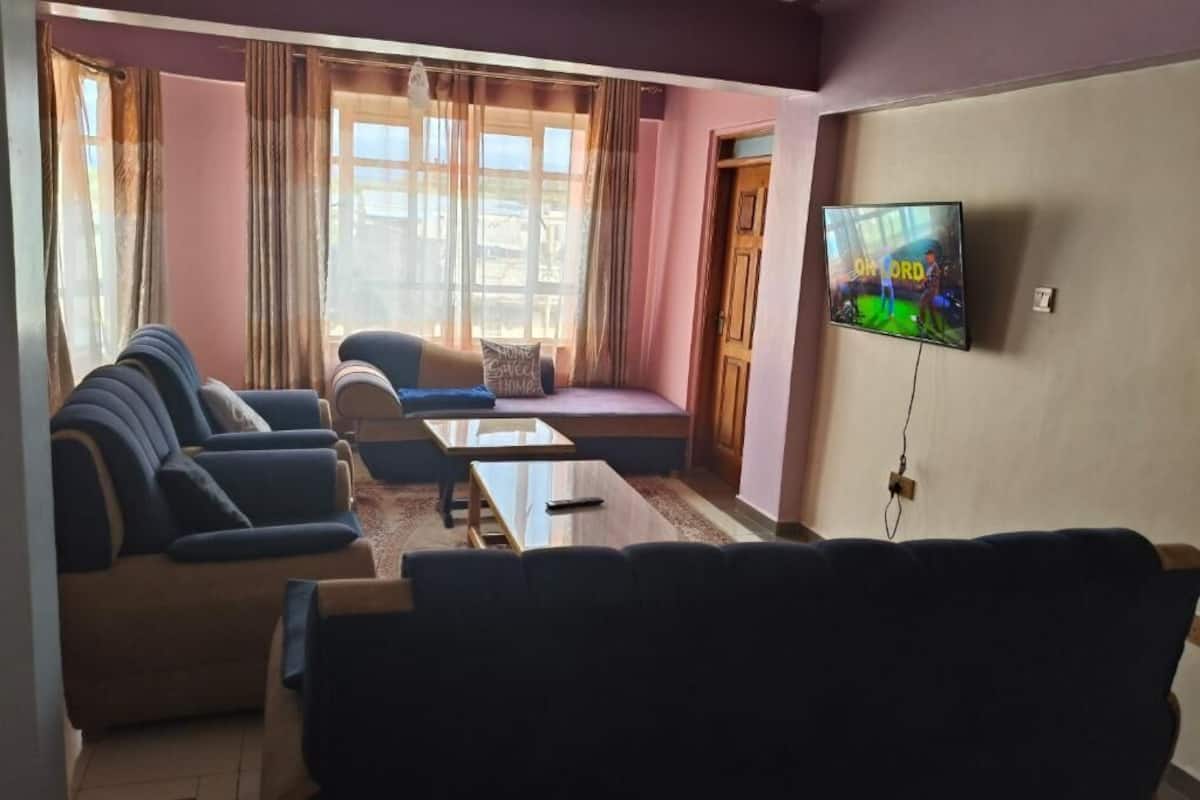 Una sala de estar con un juego de sofá, una mesa de centro y un televisor montado en la pared.