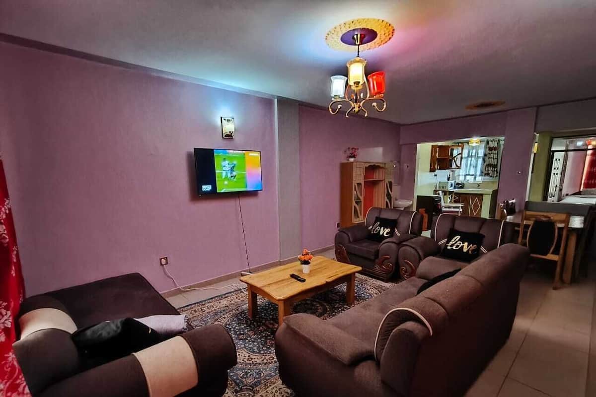 Una sala de estar con televisor, sofá y mesa de centro.
