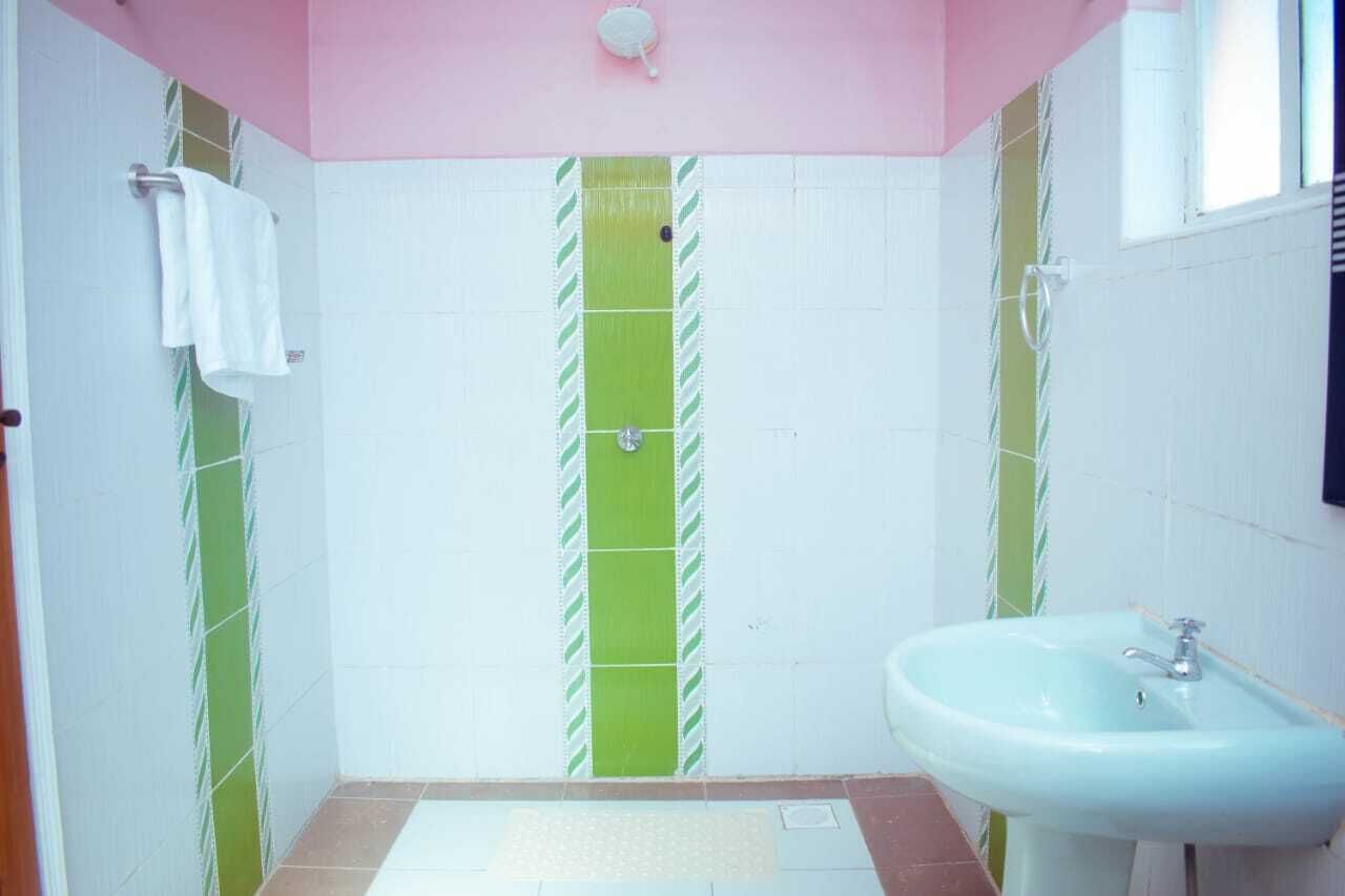 A bathroom with a pink ceiling, green and white striped tiles, a white sink, and a towel rack.