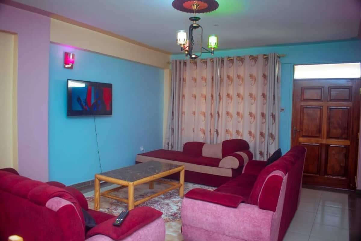 Una sala de estar con un sofá, una mesa de centro, un televisor y una cortina estampada.