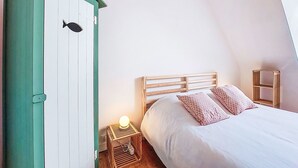 Ett sovrum med en säng, ett sängbord, en grön garderob och ett litet bord vid sängen med en lampa.