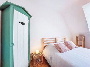 A bedroom with a bed, a nightstand, a green wardrobe, and a small bedside table with a lamp. - Le Clozic by Interhome (Locquirec)