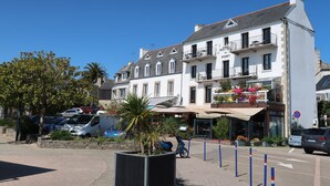 Ett hotell med en vit fasad, flera balkonger och en skylt med texten ”HOTEL DU PORT”.