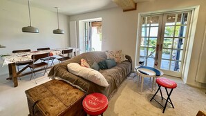 Ett mysigt vardagsrum med en soffa, ett matbord och ett stort fönster.