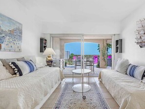 A room with two sofas, a table, a lamp, and a view of a balcony with outdoor furniture. - APARTMENT T3 NEAR THE BEACH WITH LARGE TERRACE AND SEA VIEW FOR RENT IN STE MAXIME (STE MAXIME)