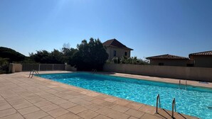 A rectangular swimming pool with clear blue water, surrounded by a tiled deck. - APARTMENT T3 NEAR THE BEACH WITH LARGE TERRACE AND SEA VIEW FOR RENT IN STE MAXIME (STE MAXIME)