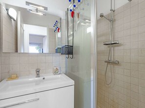 A bathroom with a white sink, a glass shower enclosure, a mirror, and a towel rack. - APARTMENT T3 NEAR THE BEACH WITH LARGE TERRACE AND SEA VIEW FOR RENT IN STE MAXIME (STE MAXIME)
