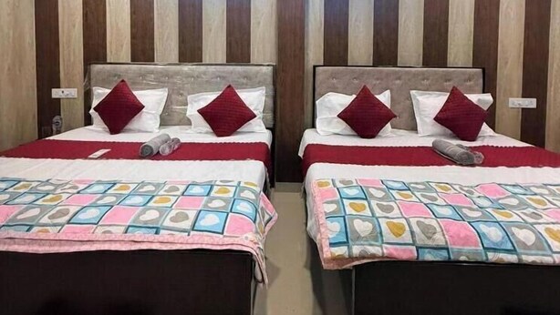 Habitación de hotel con dos camas, cada una con cubrecama y almohadas rojas y blancas. La habitación tiene paneles de madera en las paredes y un techo con diseño de estrellas.
