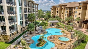 A multi-story hotel with a pool area featuring multiple pools and lounge chairs.