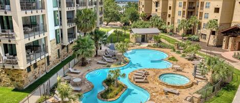 A multi-story hotel with a pool area featuring multiple pools and lounge chairs.