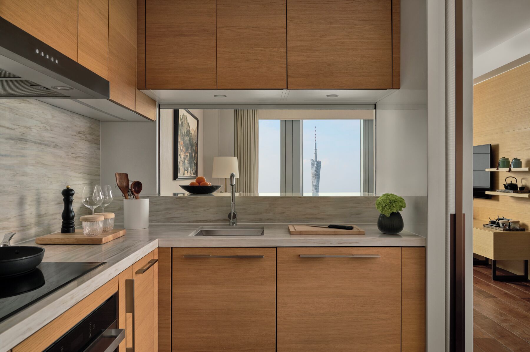 A modern kitchen with wooden cabinets, a marble backsplash, and a window with a cityscape view.