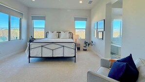 Un dormitorio con cama, sofá y ventanas amplias.