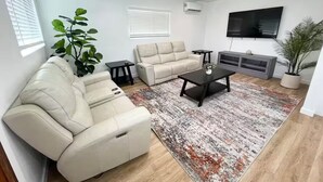 Moderni olohuone, jossa on beigenvärinen sohva, sohvapöytä ja televisio.