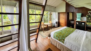 A bedroom with a bed, a wooden ladder, a window, and a door.