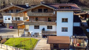 A multi-story chalet with a balcony, a small attached garage, and a well-maintained lawn. - Lovingly furnished apartement with bbq (Zellberg)