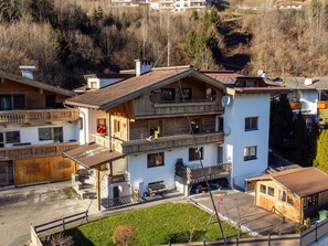 Una chaleta de varios pisos con balcones, una terraza de madera y un pequeño jardín.