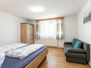 Un dormitorio con cama, armario, sofá y ventana con cortinas.