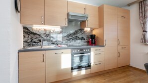 A modern kitchen with wooden cabinets, a built-in oven, and a coffee maker. - Lovingly furnished apartement with bbq (Zellberg)