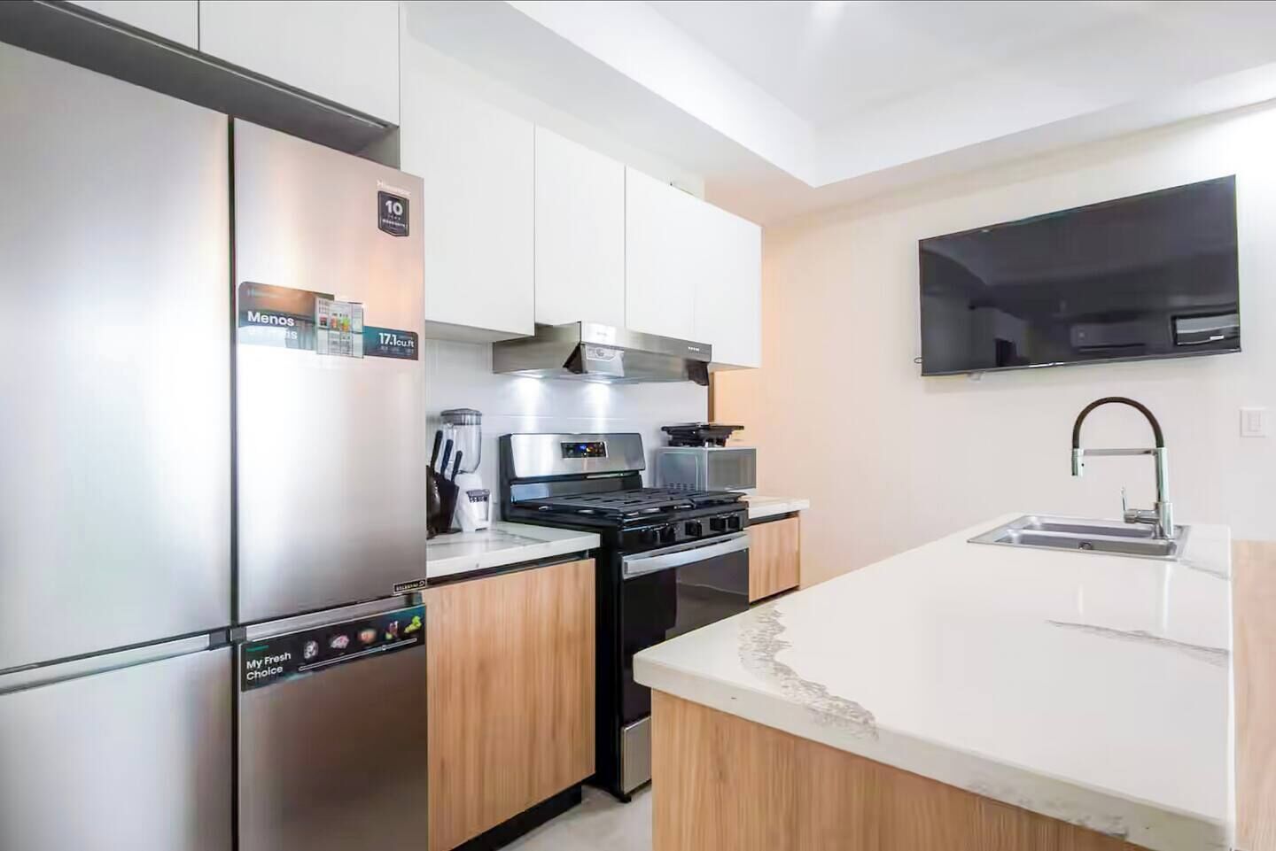 A modern kitchen with stainless steel appliances, a built-in oven, and a large island with a sink.