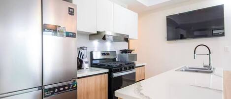 A modern kitchen with stainless steel appliances, a built-in oven, and a large island with a sink.