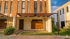 A modern building with a wooden facade, large windows, and a covered entrance area. - Villa in Vistacana Private Pool Golf Beach (Punta Cana)