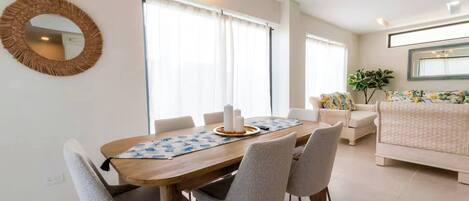 A dining area with a wooden table, grey chairs, and a round mirror on the wall.