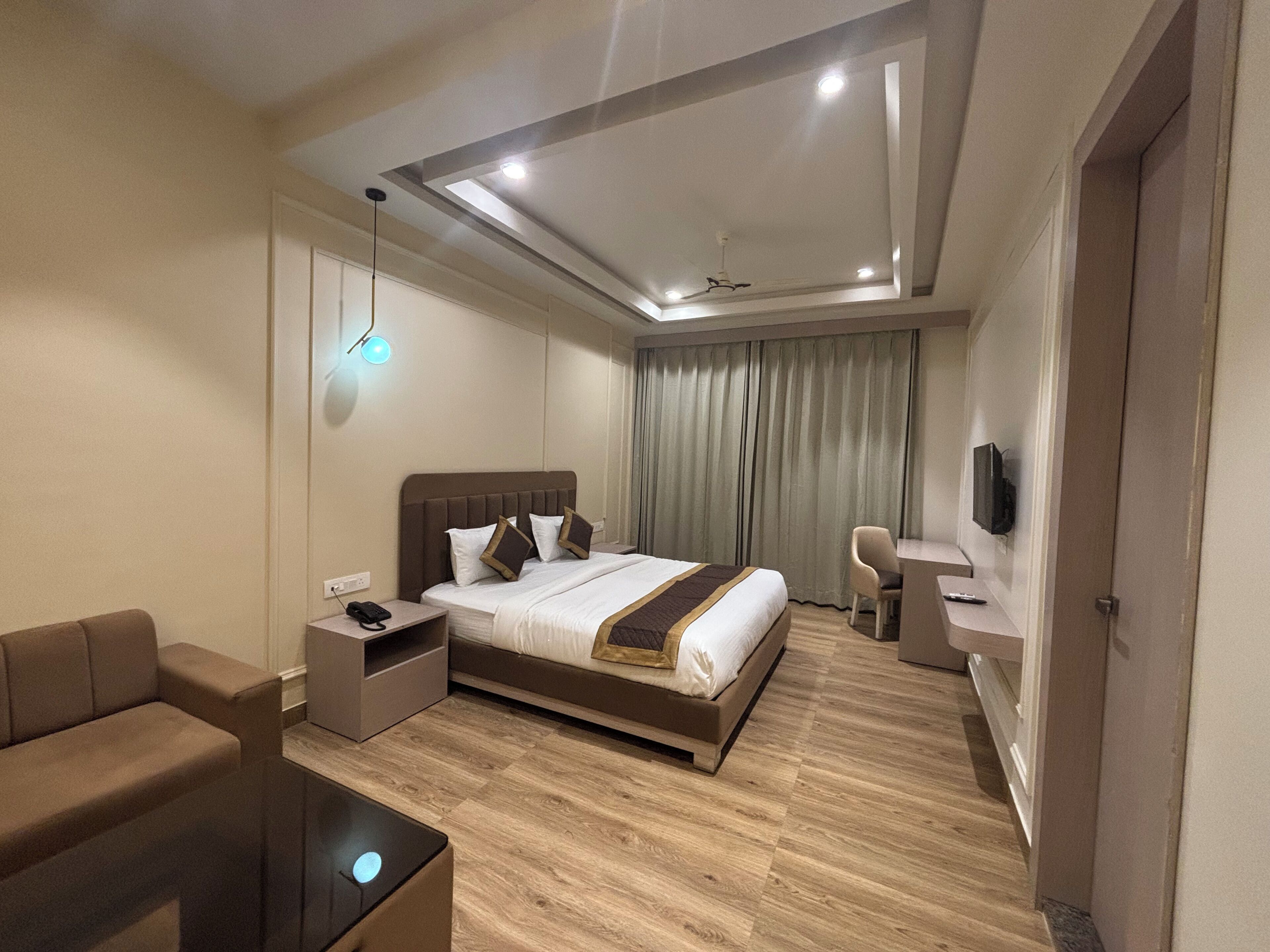 Ein modernes Hotelzimmer mit einem großen Bett, einem Schreibtisch, einem Stuhl und einem Fernseher.