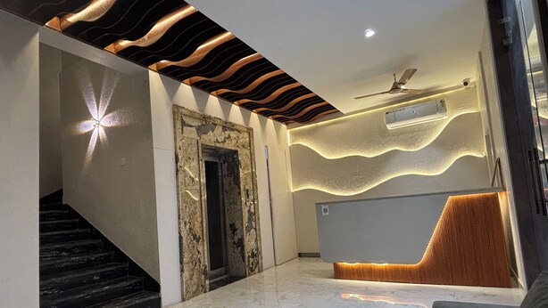 A modern lobby with a marble floor, a reception desk, a staircase, and a ceiling fan. - Hotel Shree Rajasthan Inn (Ajmer)