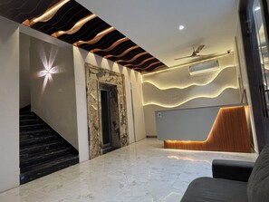 A modern lobby with a marble floor, a reception desk, a staircase, and a ceiling fan. - Hotel Shree Rajasthan Inn (Ajmer)