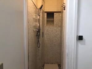 Een kleine badkamer met een douche en betegelde wanden.