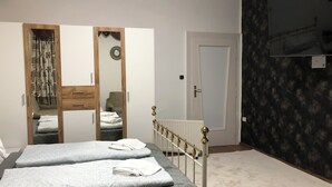 Een slaapkamer met een bed, een kledingkast, een radiator en een televisie aan de muur.