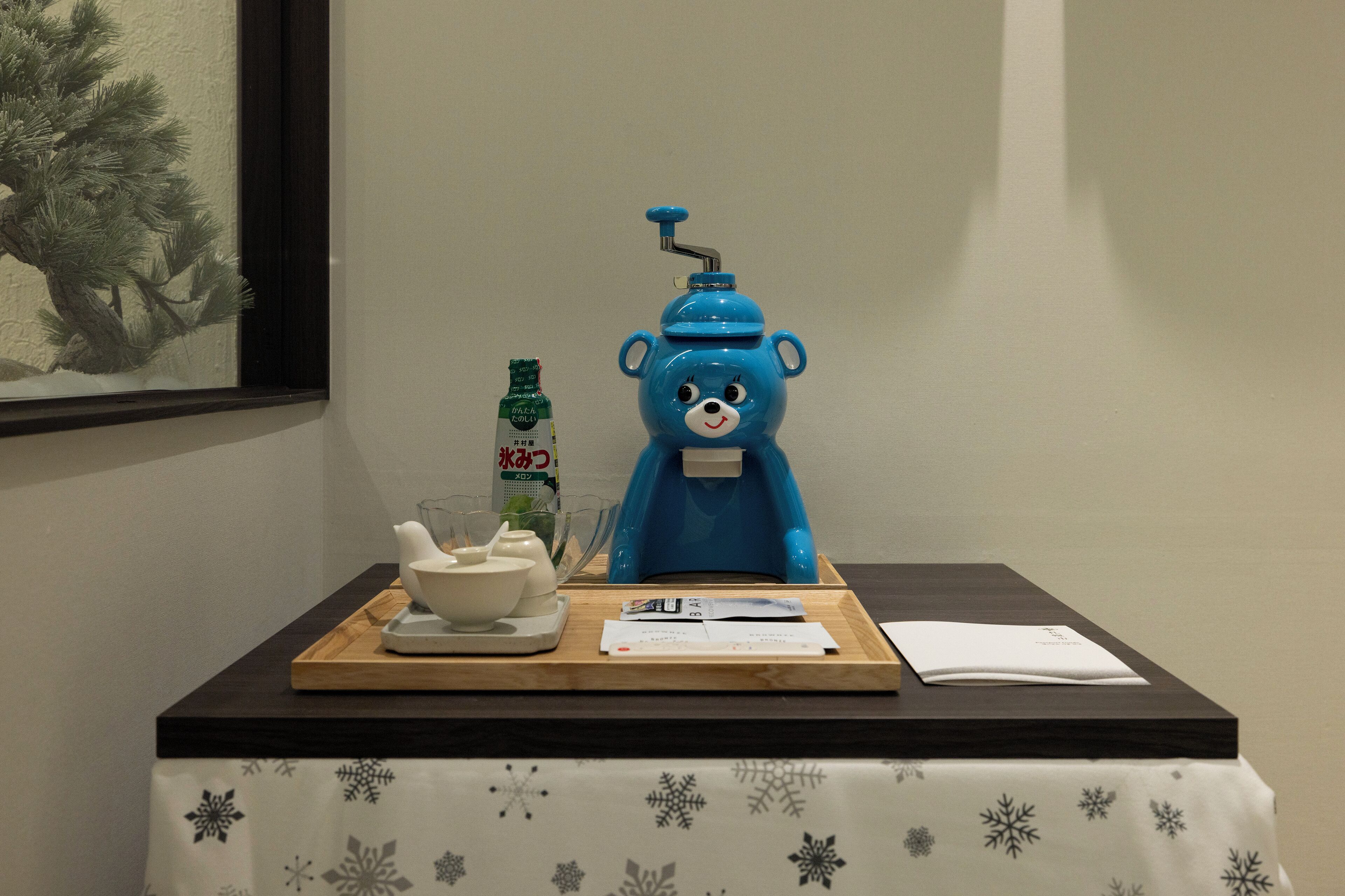 A table with a bear-shaped water dispenser, a bottle of water, a bowl, and some papers.