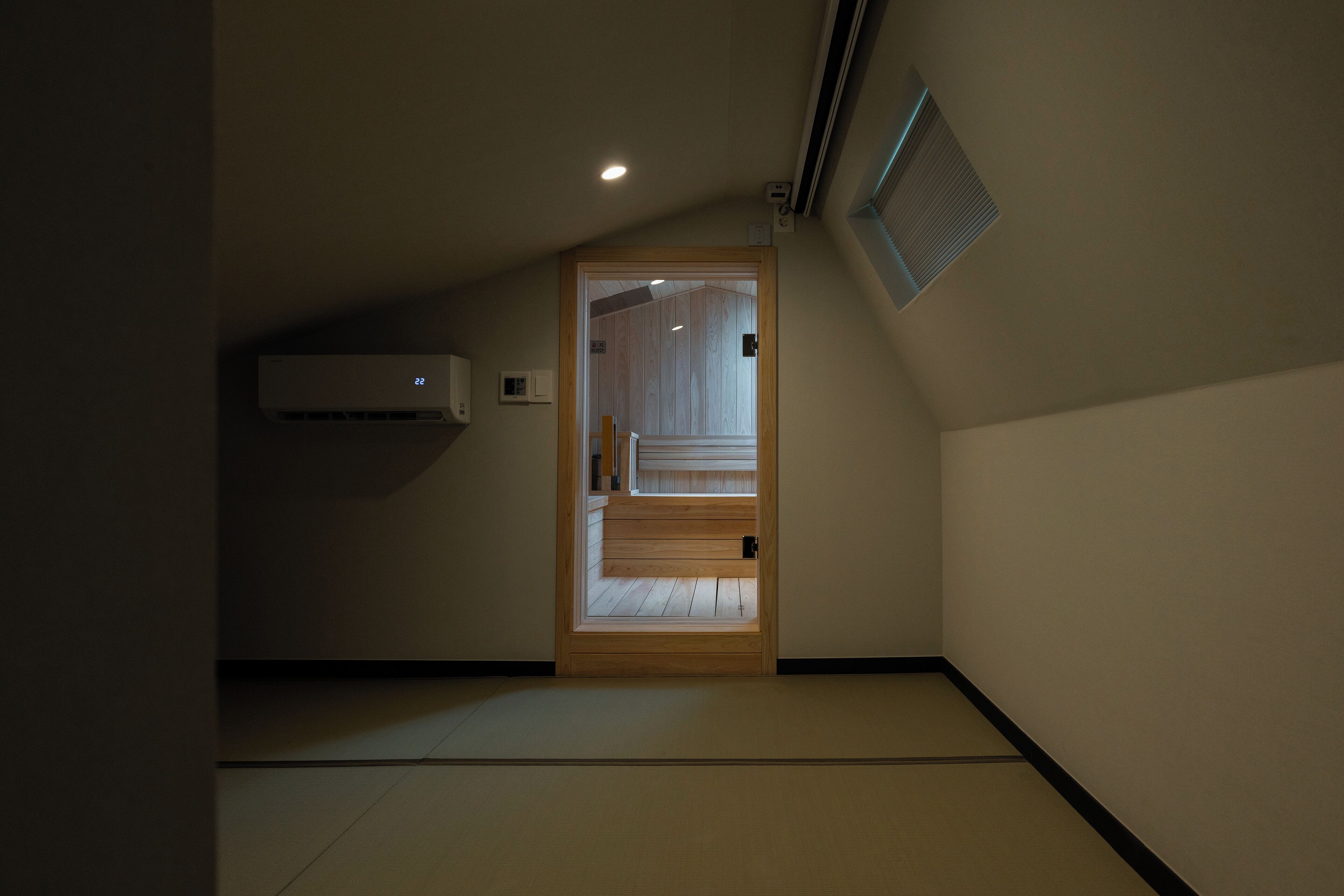 A narrow hallway with a wooden door leading to a room with tatami flooring.