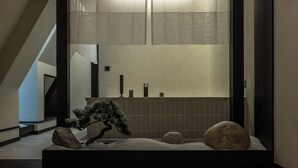 Un intérieur japonais traditionnel avec un sol recouvert de tatamis, un bonsaï et un jardin de pierres.