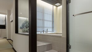 Un couloir d’hôtel donnant sur une fenêtre, un lavabo et un escalier.