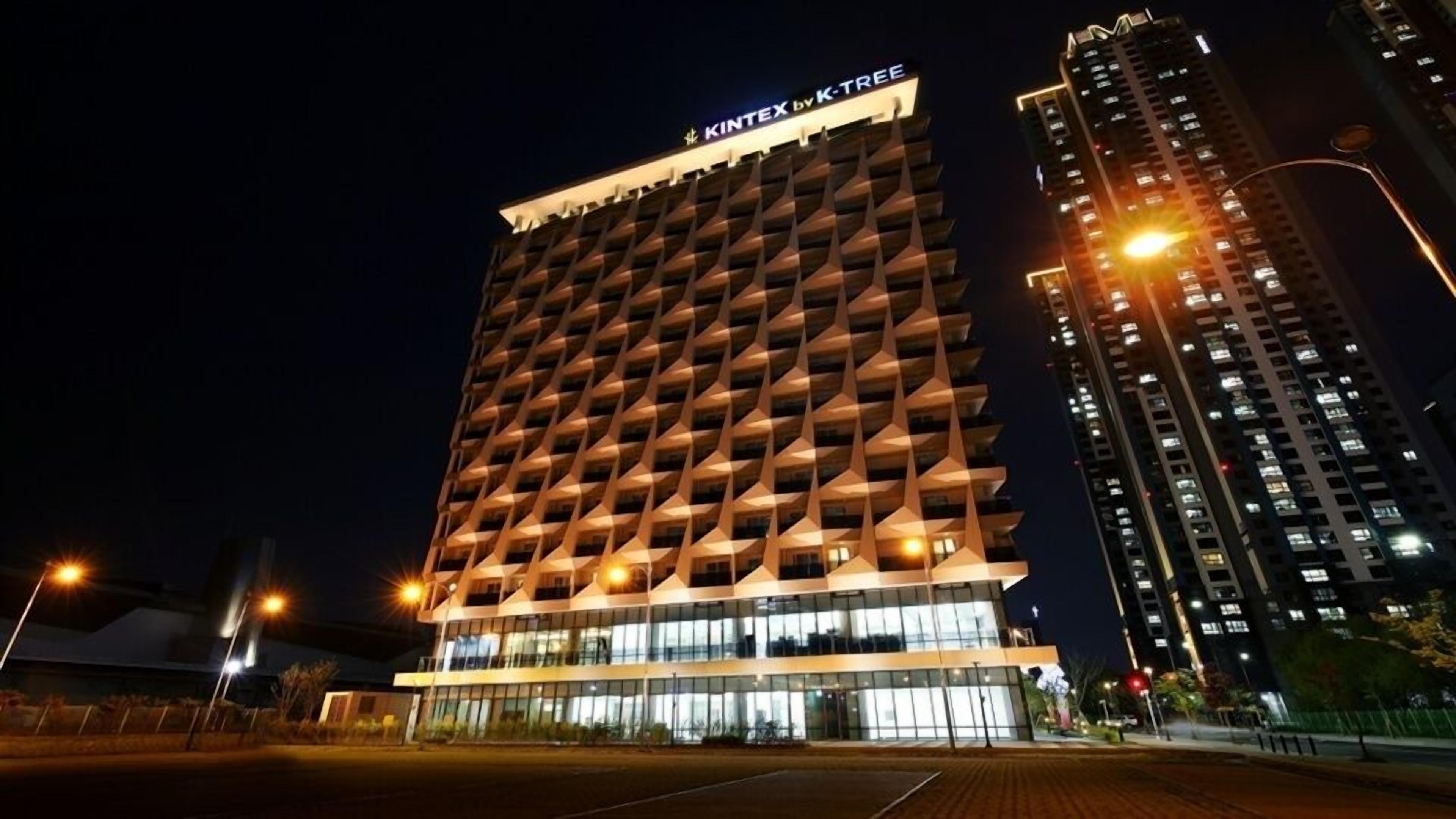 A modern hotel with a unique geometric facade and illuminated signage.