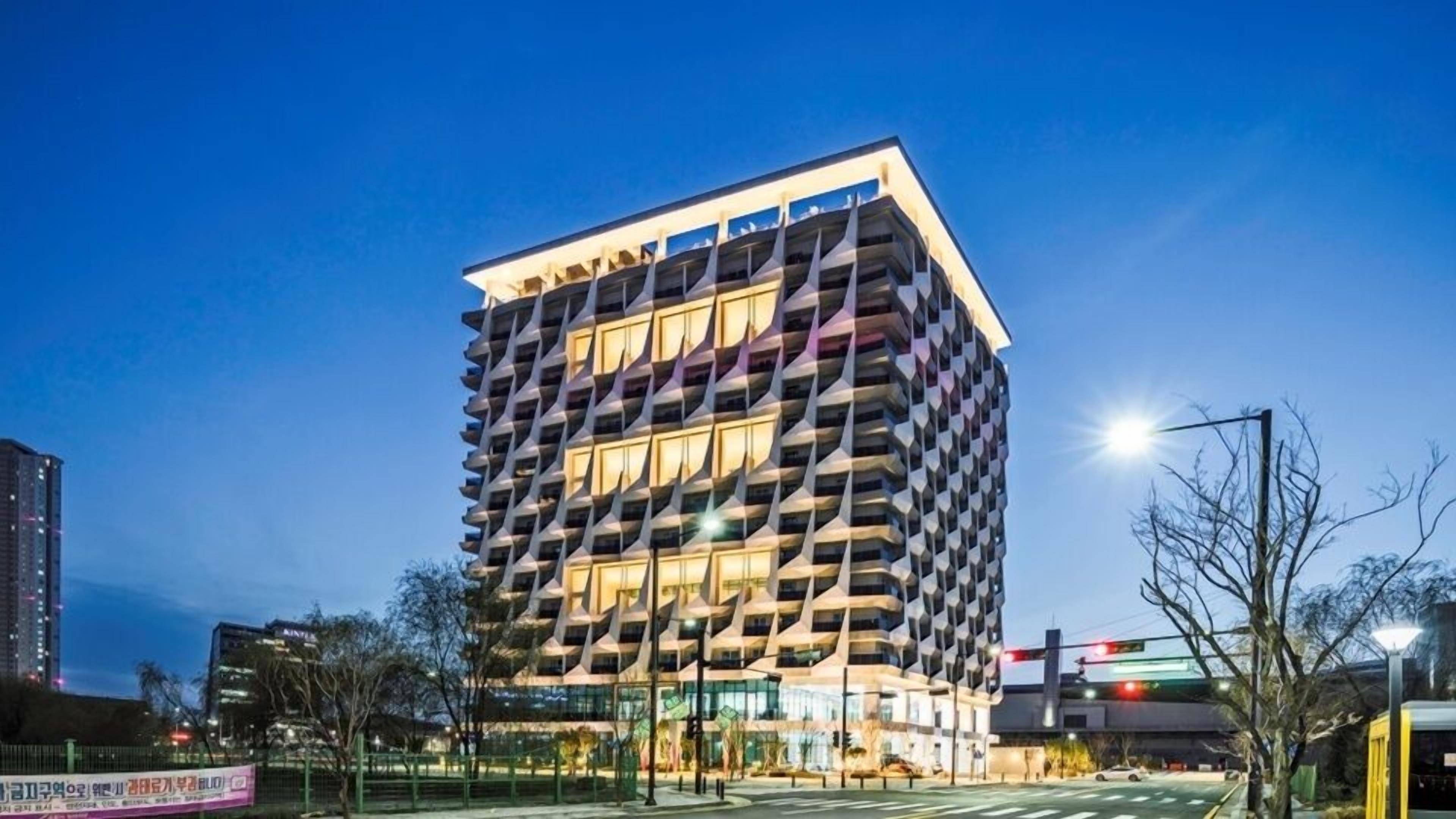 A modern high-rise building with a unique geometric facade, multiple balconies, and large windows.