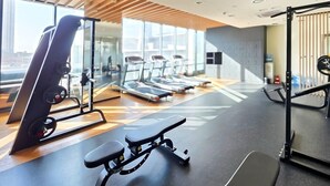 Une salle de sport équipée de tapis de course, d’un support pour les exercices de squat et d’un banc de développé couché.