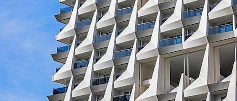 A modern high-rise building with a unique geometric facade and balconies.