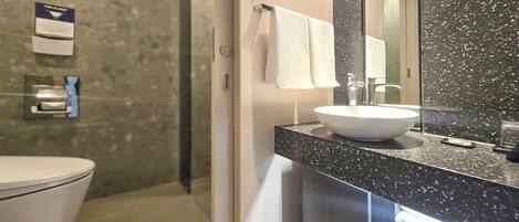 Un baño moderno con un lavamanos blanco, un espejo grande y un inodoro.