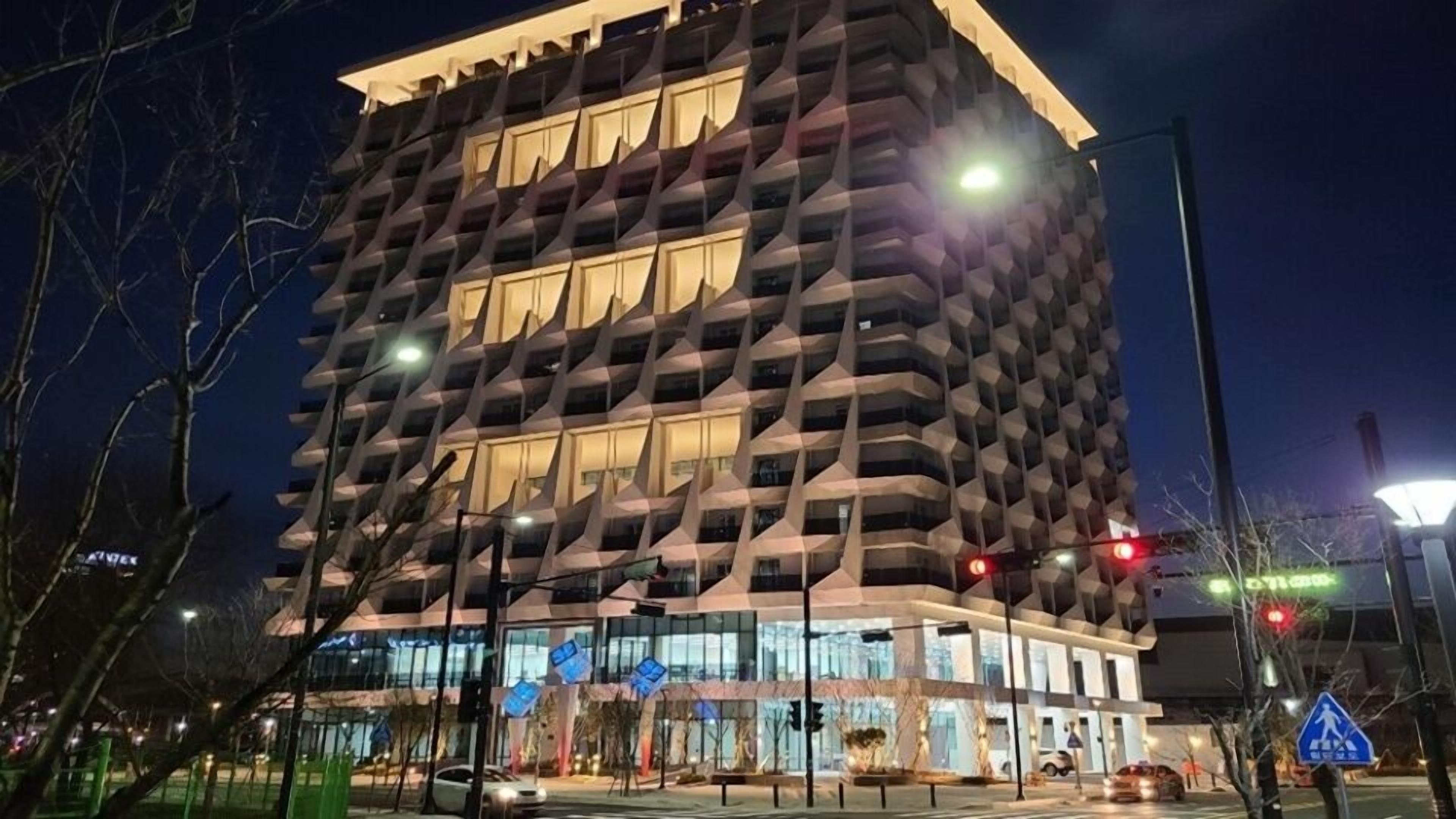 A modern high-rise building with a unique geometric facade and multiple balconies.