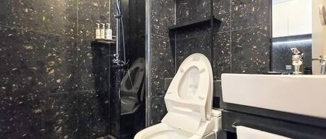 Un baño moderno con inodoro blanco, zona de ducha e lavabo.