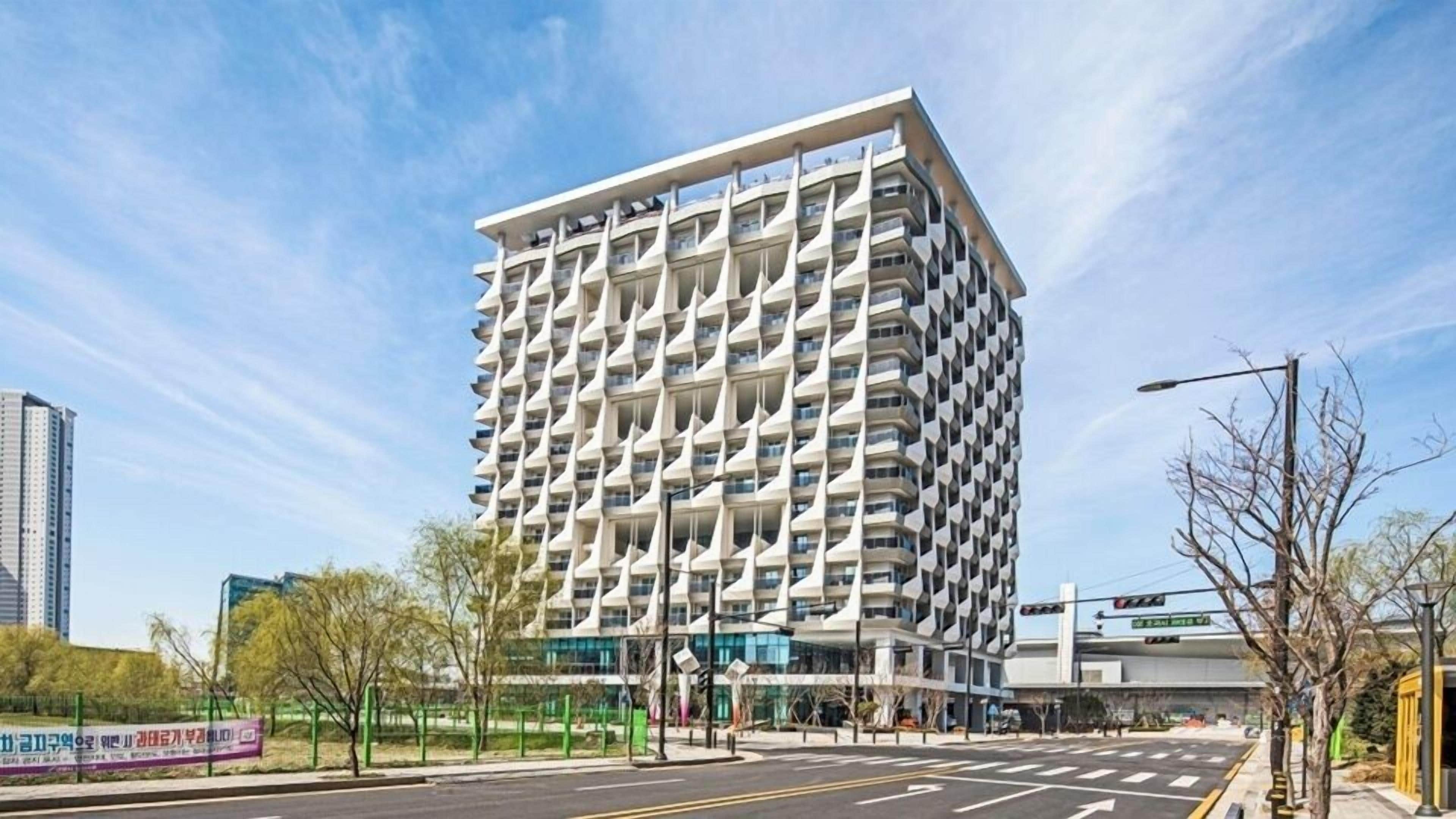 A modern high-rise building with a unique architectural design, featuring a grid-like facade and multiple balconies.
