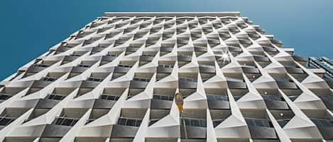 Un edificio de gran altura con una fachada geométrica distintiva, que presenta un patrón repetido de formas triangulares y un elemento vertical central.