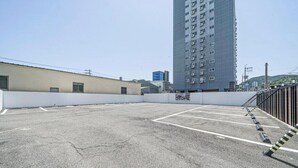 Un parking avec des places délimitées et un grand immeuble en arrière-plan.