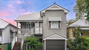 A two-story house with a front porch, a garage, and a staircase leading to the upper floor. - Elegant Dual-Level Home Near Cafés, Parks & River (East Brisbane)