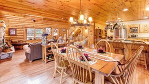 A wooden cabin interior with a dining area, kitchen, and living space. - Spacious Log Home w/ 13 Acres, Ponds & Fire Pit! (Kingsley)
