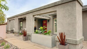 A modern building with a concrete facade, large planters with plants, and a red door. - Close to Hiking! Snowbird Haven w/ Pool in Phoenix (Phoenix)