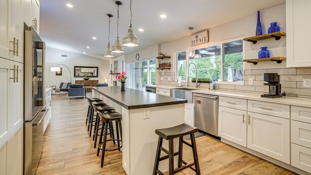 A modern kitchen with a central island, bar stools, stainless steel appliances, and wooden flooring. - Close to Hiking! Snowbird Haven w/ Pool in Phoenix (Phoenix)